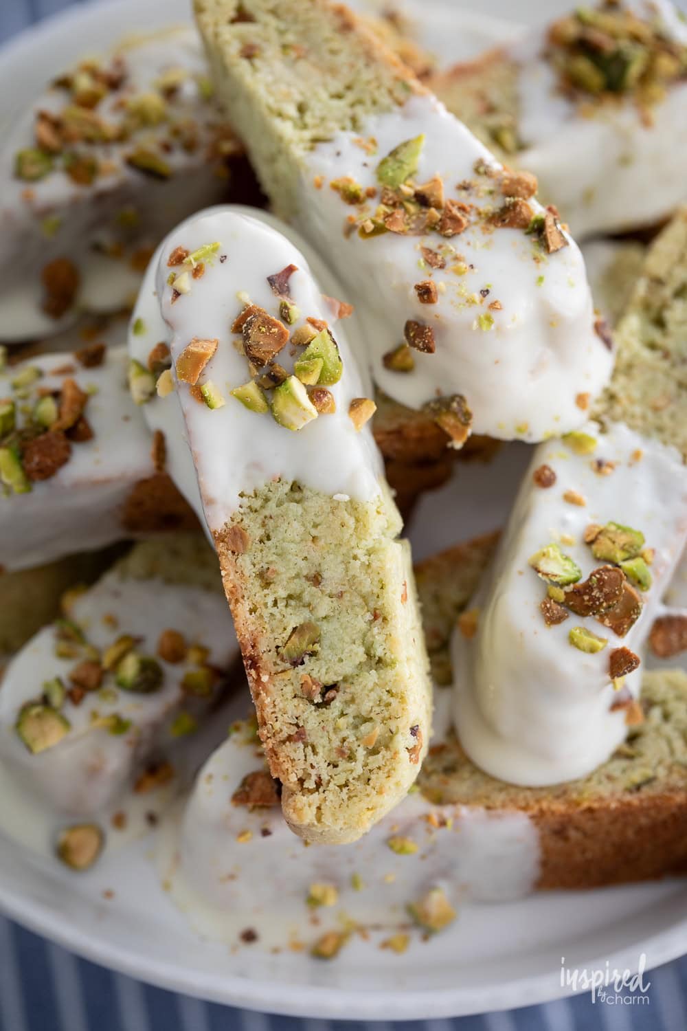 White chocolate pistachio biscotti topped with crushed pistachios and a white chocolate glaze